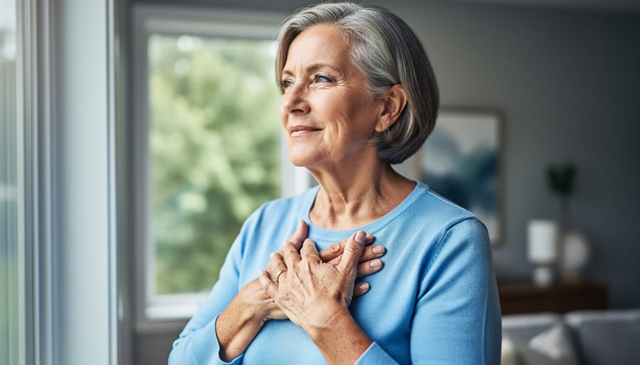 Canadian woman in her early 50s holding her hands over her chest near a window, representing heart health during perimenopause and menopause.